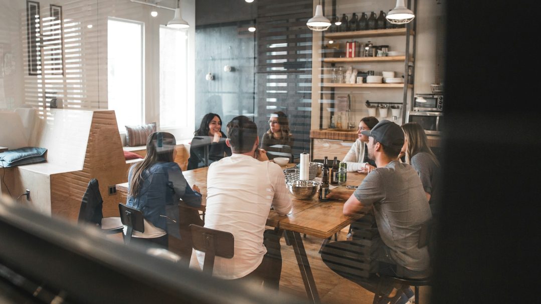 TPE au travail Un groupe de personnes assises autour d'une table dans un espace de travail convivial.